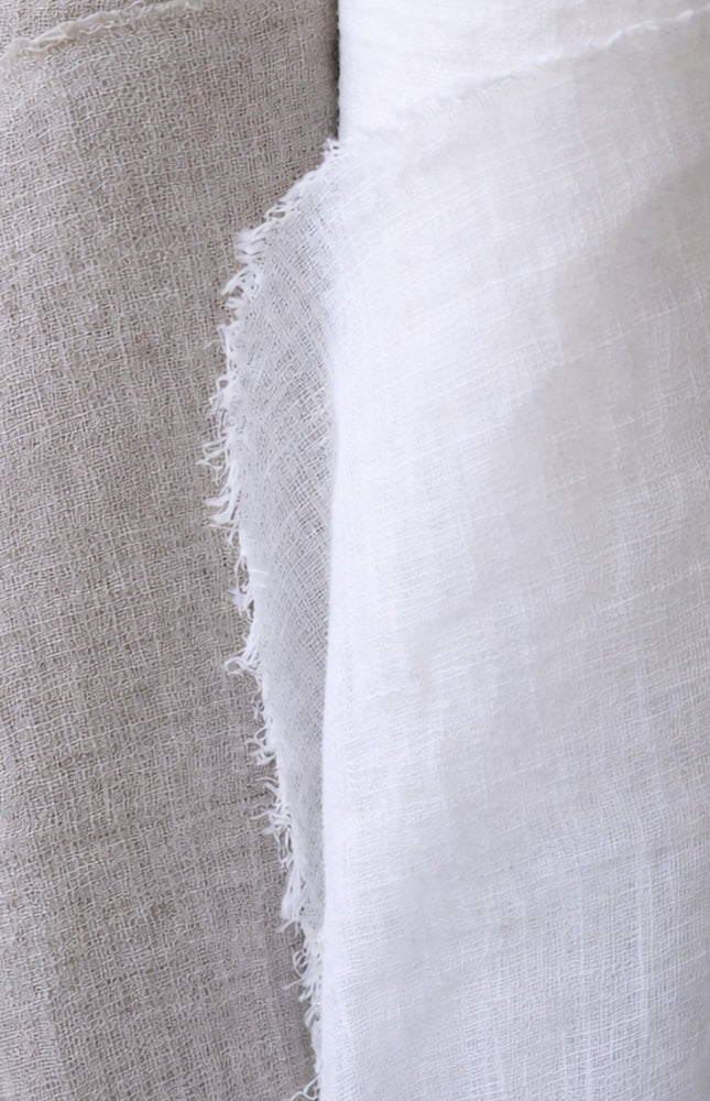 Two rolls of fabric, one gray and one white, on a gray background.